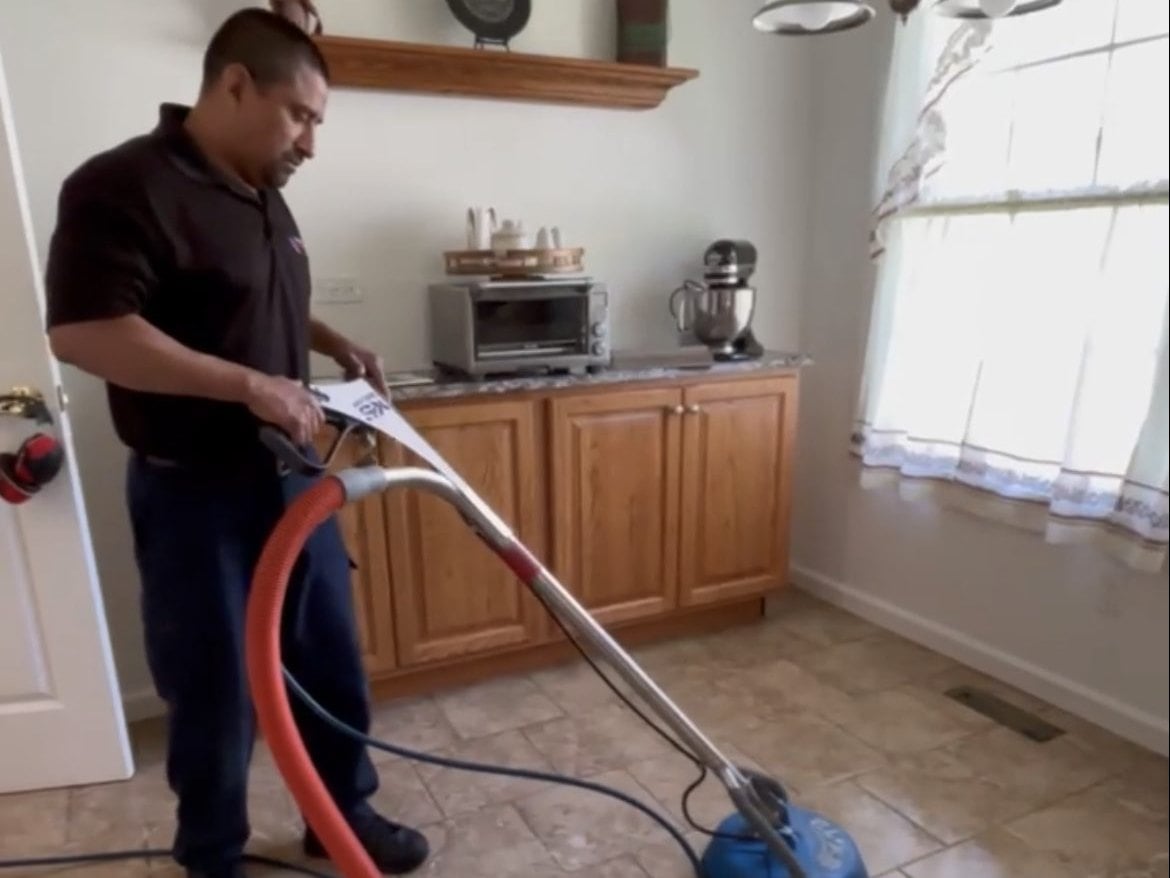 Technician steam cleaning a tile floor