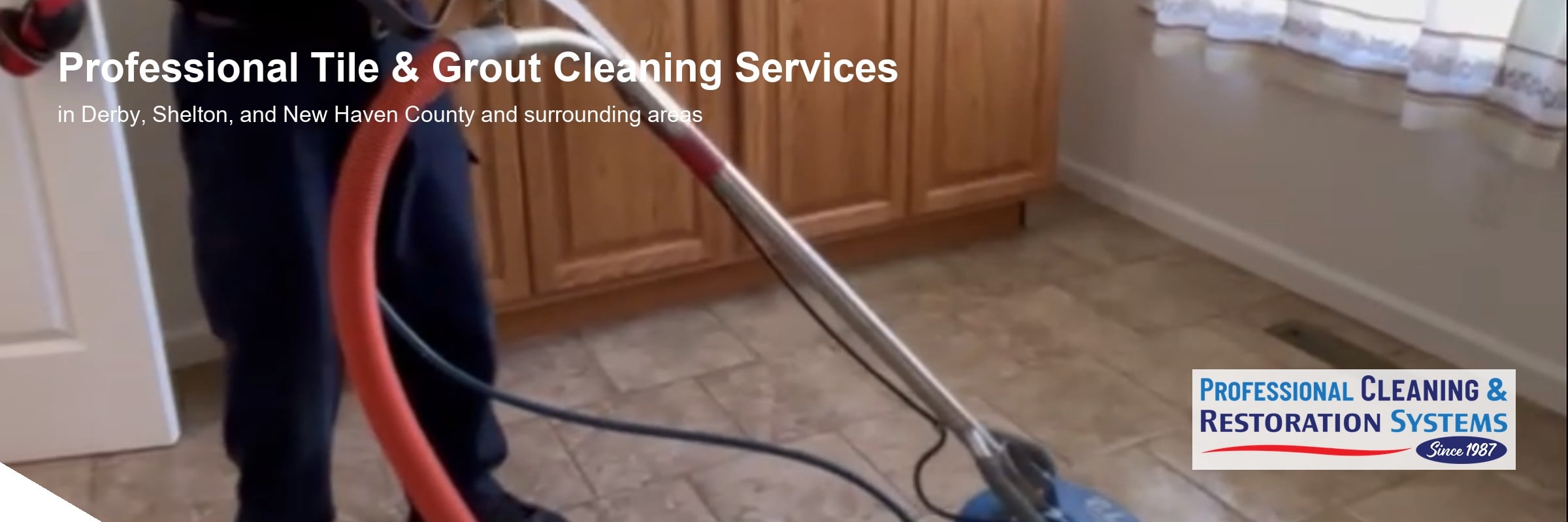 pcrs-tile-grout-cleaning-banner Tile and grout cleaning in Derby CT — a PCRS technician running a rotary spinner tool across a travertine tile kitchen floor, red solution hose in shot