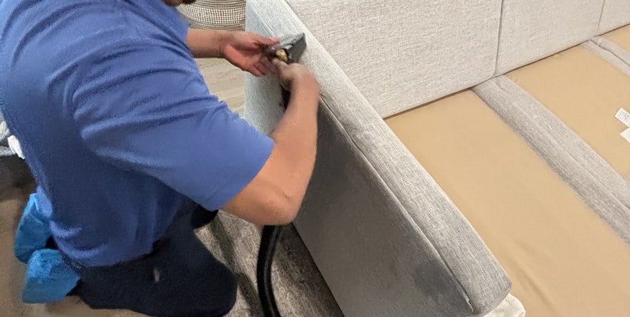 Technician using a hand tool to deep clean a mattress